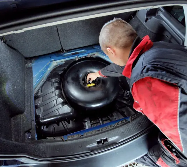 Mechanik sprawdza butlę LPG w bagażniku. Dowiedz się, ile kosztuje legalizacja butli LPG i jakie są formalności.