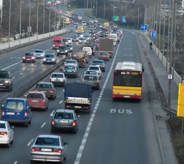 Autobus jedzie pasem dla autobusów. Wokół ruch samochodowy.