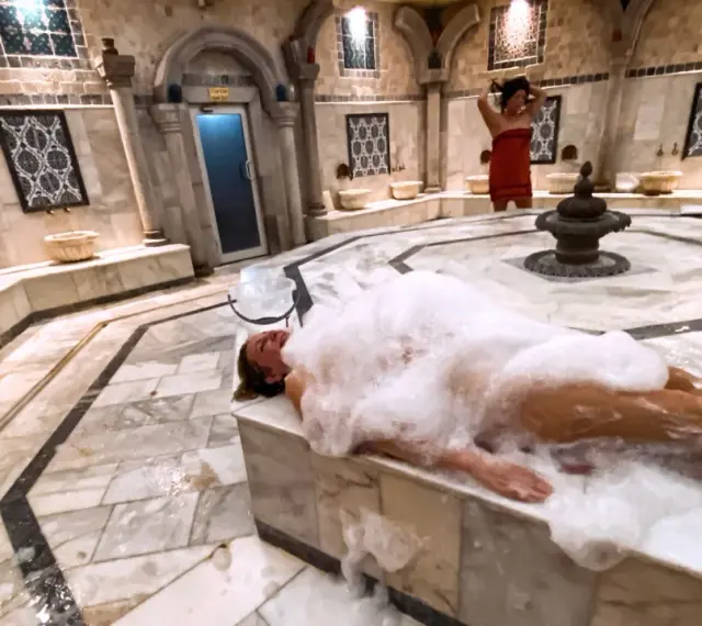 Kobieta w pianie w łaźni hammam. To tradycyjne tureckie łaźnie parowe, miejsce relaksu i oczyszczenia.