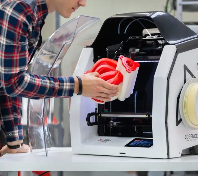 Inżynier wyjmuje z drukarki 3D skomplikowany element, pokazując potencjał druku 3D w przemyśle.