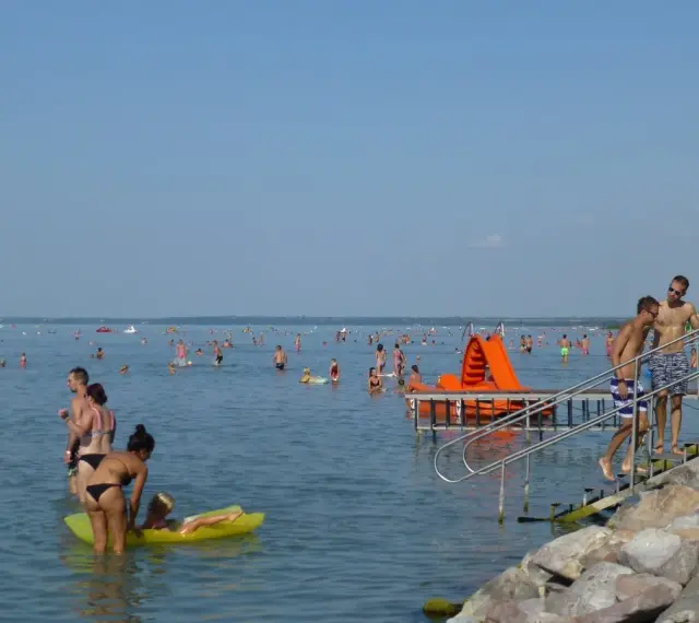 Tłum ludzi cieszy się kąpielą w Balatonie. Idealna temperatura wody zachęca do zabawy na dmuchanych zabawkach i zjeżdżalniach.