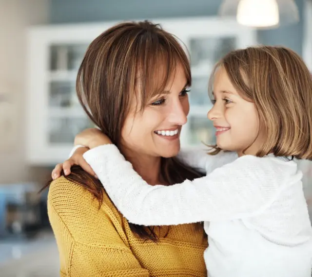 Uśmiechnięta mama i córka przytulają się, emanując ciepłem i bliskością. To kwintesencja rodzicielstwa bliskości.
