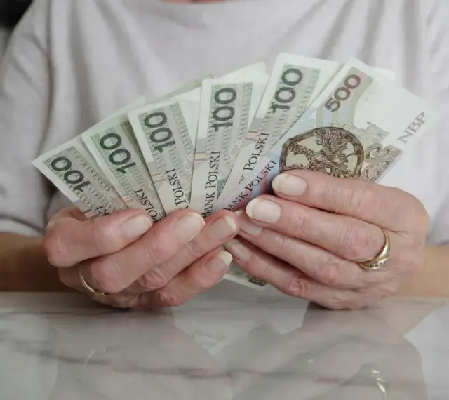 Dłonie trzymające polskie banknoty 100 i 500 zł. Numerologia 8 z dnia urodzenia może symbolizować stabilność finansową.