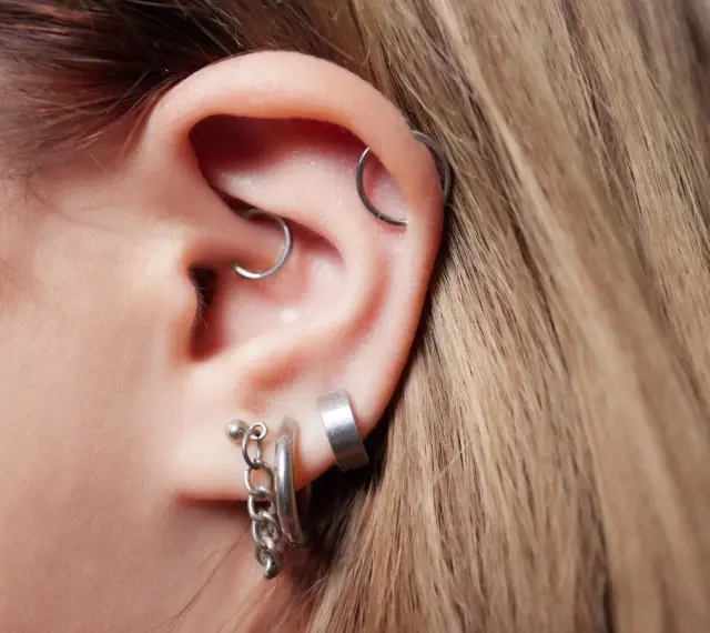 Ucho z kilkoma kolczykami, w tym modnym daith piercingiem.