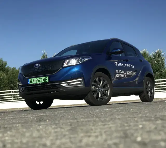 Niebieski SUV Seres 3 zaparkowany na zewnątrz, z widocznym logo i napisem.