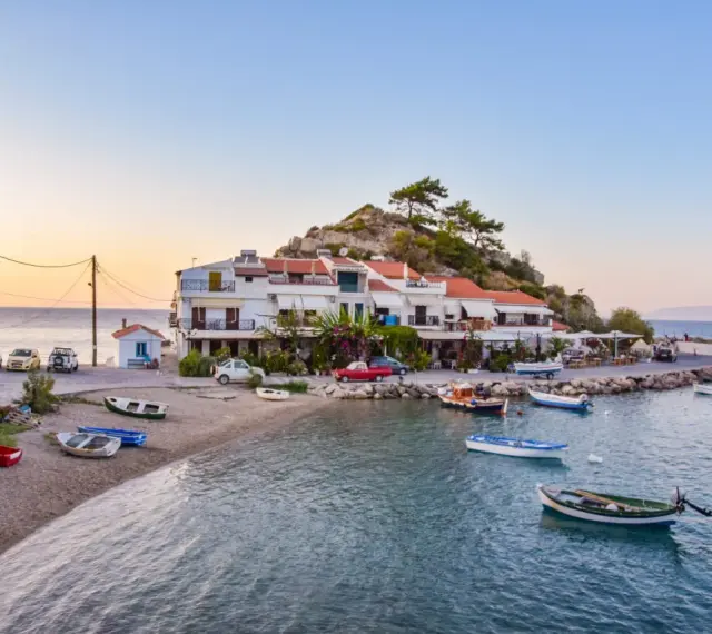 Widok na zatokę Vathy na Samos z łodziami i budynkami na tle wzgórza.