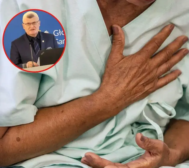Lekarz omawia objawy grypy wariant K. Pacjent trzyma się za klatkę piersiową, odczuwając dyskomfort.