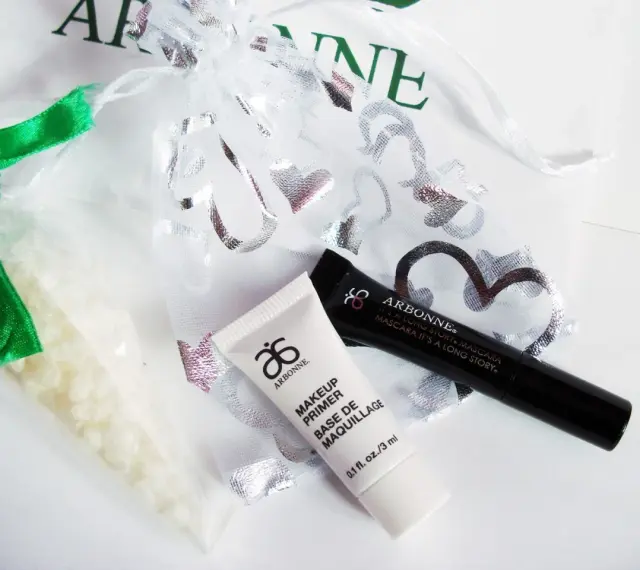 Arbonne opinie: zestaw kosmetyków z primerem i tuszem, w ozdobnym woreczku.