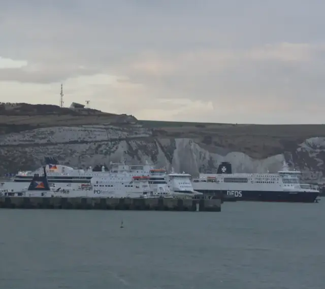 Promy z samochodami czekają na rejs do Anglii. Zastanawiasz się, ile kosztuje prom do Anglii z samochodem? Widok na białe klify Dover.