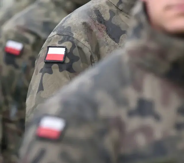 Żołnierze w mundurach moro z polskimi flagami na ramionach, gotowi do służby lub po latach zasłużonej emerytury wojskowej.