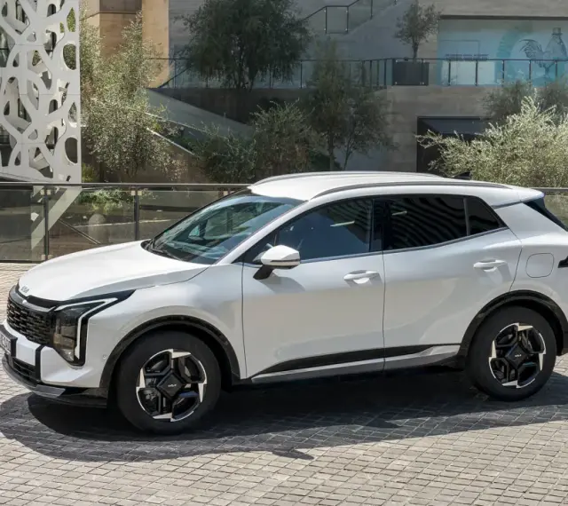Biała Kia Sportage hybryda na tle nowoczesnej architektury. Stylowy SUV gotowy na miejskie wyzwania.