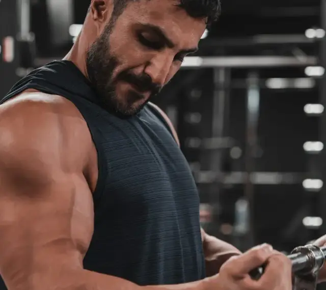 Mężczyzna ćwiczy biceps na siłowni. Zastanawia się nad cytrulina skutki uboczne, ale skupia się na treningu.