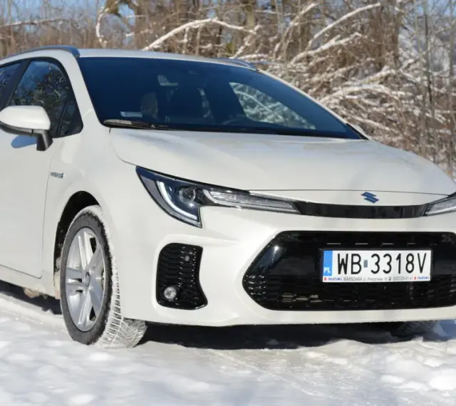 Biały Suzuki Swace Hybrid na śniegu, gotowy na zimowe wyzwania.