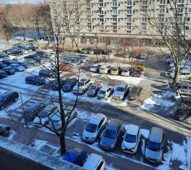 Zimowy parking pod blokiem z lat 90. pokazuje, dlaczego mieszkańcy mają problem z parkowaniem. Auta upchnięte na każdym wolnym skrawku ziemi.
