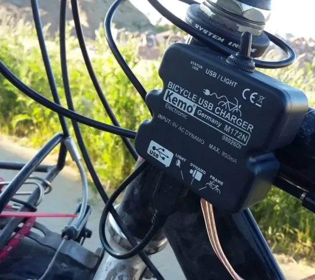 Ładowarka rowerowa Kemo zasilana przez **dynamo**, podłączona do kierownicy, z kablem USB.