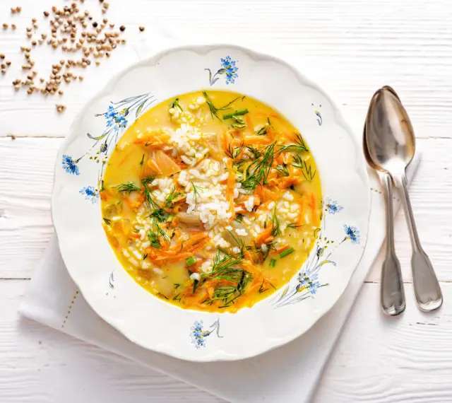 Aromaticzna zupa koperkowa z ryżem, marchewką i kawałkami kurczaka, udekorowana świeżym koperkiem.