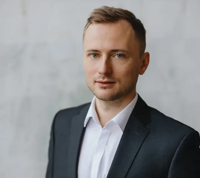Mężczyzna w garniturze i białej koszuli, idealny przykład, jak zrobić zdjęcie biznesowe w domu.