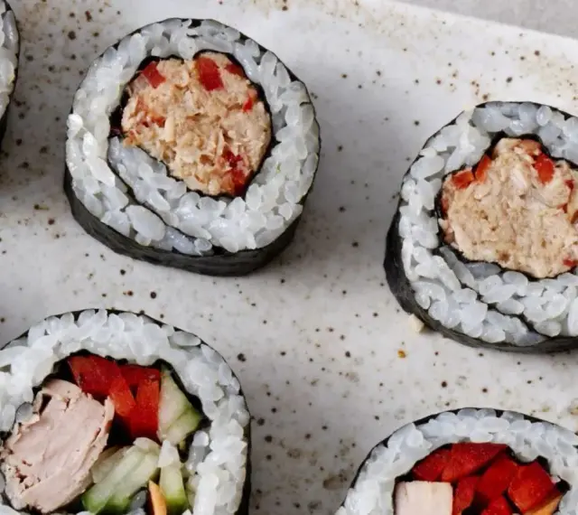 Kilka kawałków sushi z tuńczykiem i warzywami na talerzu.