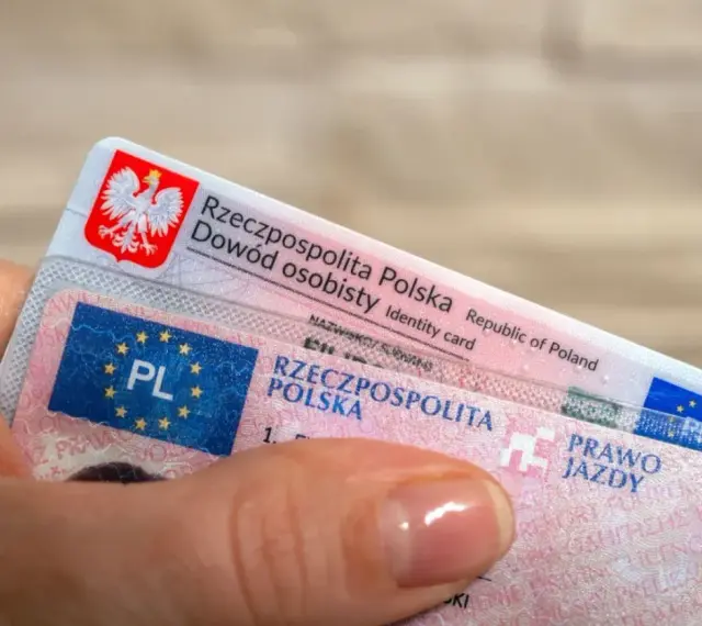 Dłoń trzyma polski dowód osobisty i prawo jazdy. To dokumenty, które pozwalają na swobodne podróżowanie, a prawo jazdy bezterminowe daje spokój na lata.