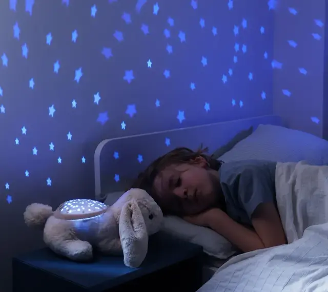 Uroczy króliczek z projektorem dla niemowlaka rzuca na ścianę niebieskie gwiazdki, tworząc magiczną atmosferę do snu.