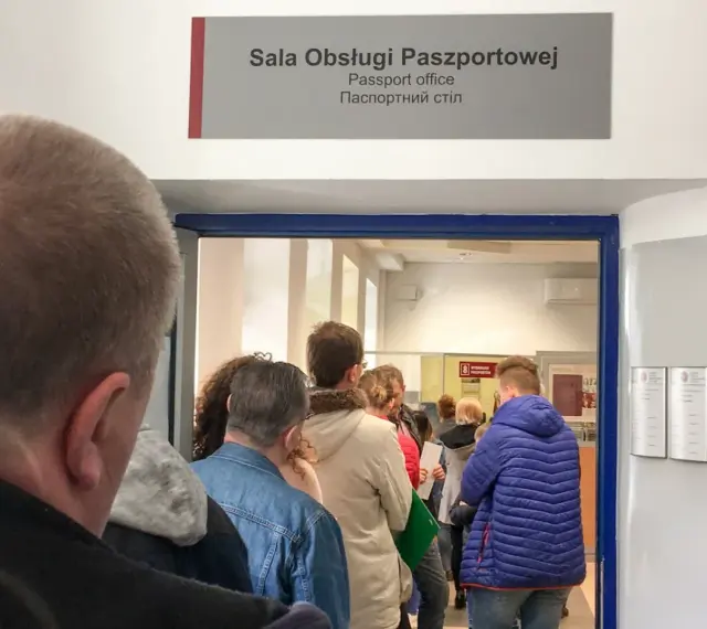 Kolejka do sali obsługi paszportowej. Czy odbiór paszportu musi być osobiście? Ludzie czekają w środku i na zewnątrz.