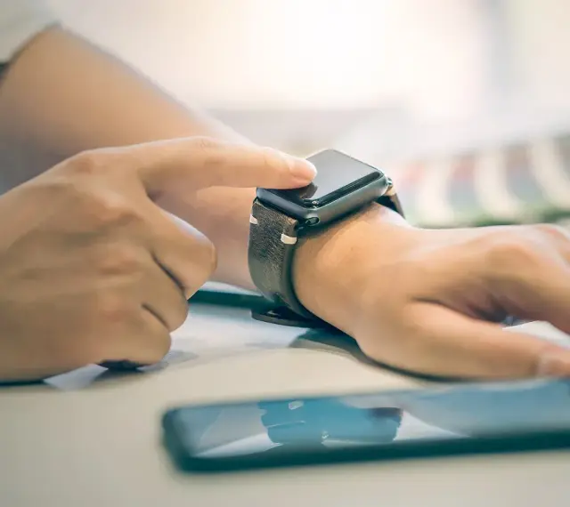 Dłoń z zegarkiem na nadgarstku, palec dotyka ekranu, pokazując jak włączyć bluetooth w smartwatch.