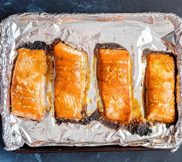Cztery kawałki łososia pieczone na folii aluminiowej, gotowe do dalszego przygotowania, np. jak przygotować łososia do sushi.