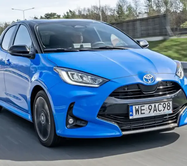 Błękitna, nowa Toyota Yaris z czarnym dachem pędzi po drodze.