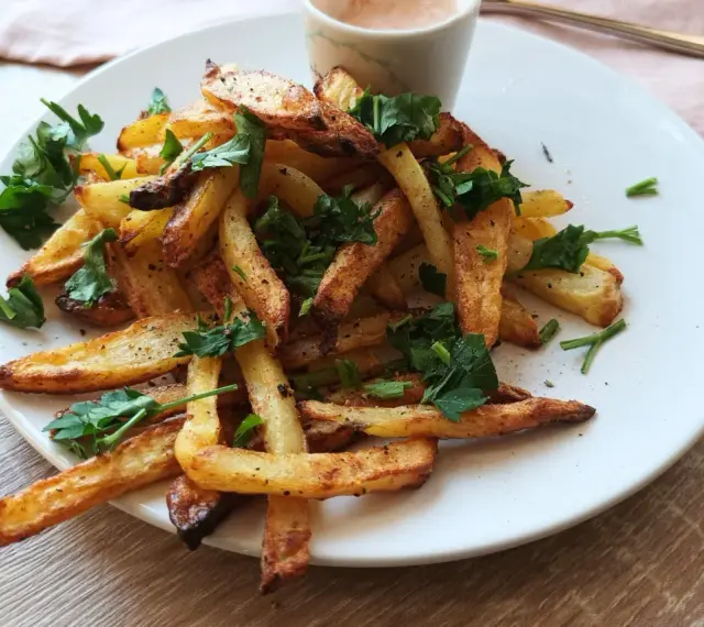 Chrupiące frytki z air fryera, posypane natką pietruszki. Idealne na szybki obiad, proste air fryer przepisy obiad.