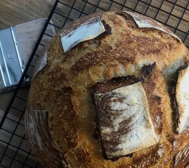 Chleb pszenno żytni na zakwasie, pachnący świeżością, czeka na ostygnięcie. Obok pędzel do pieczenia.