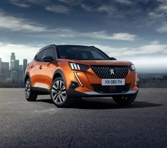 Pomarańczowy Peugeot 2008 na tle miasta. Sprawdź jego wymiary i możliwości.