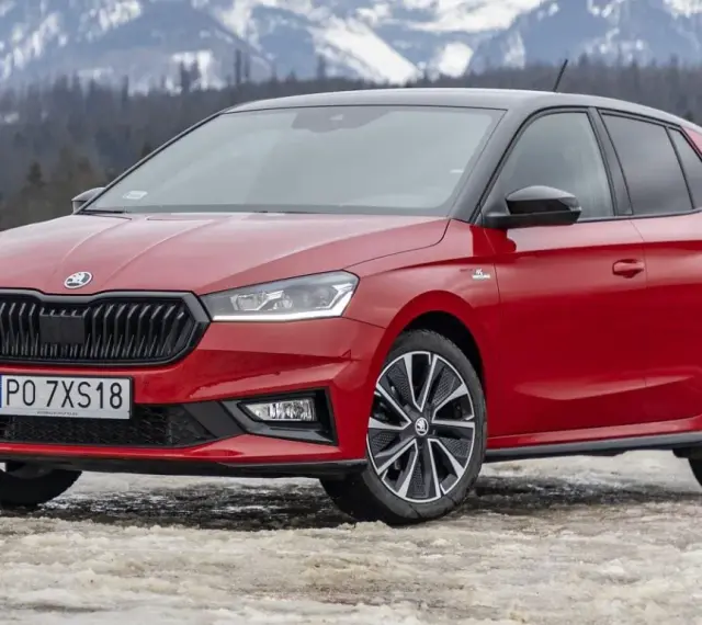 Czerwona Skoda Fabia Monte Carlo z czarnym dachem na tle ośnieżonych gór.