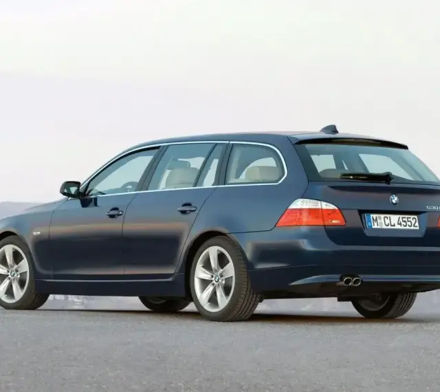 Granatowe BMW E61, kombi, stoi na pustej drodze.