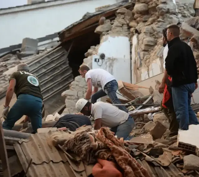 Ratownicy przeszukują gruzy po trzęsieniu ziemi we Włoszech. Zniszczone budynki i chaos po katastrofie.