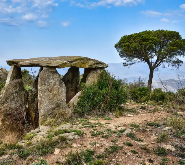 Starożytny menhir, kamienna konstrukcja, stoi na wzgórzu pod błękitnym niebem.