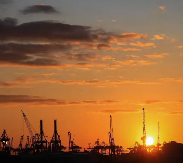 Silhouetten von Kränen im Hamburger Hafen bei Sonnenuntergang. Perfekt für die Pfingstferien in Hamburg.