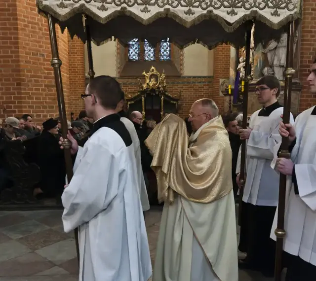 Uroczysta procesja w kościele, kapłan niesie monstrancję okrytą złotym welonem. To symboliczna rezurekcja.
