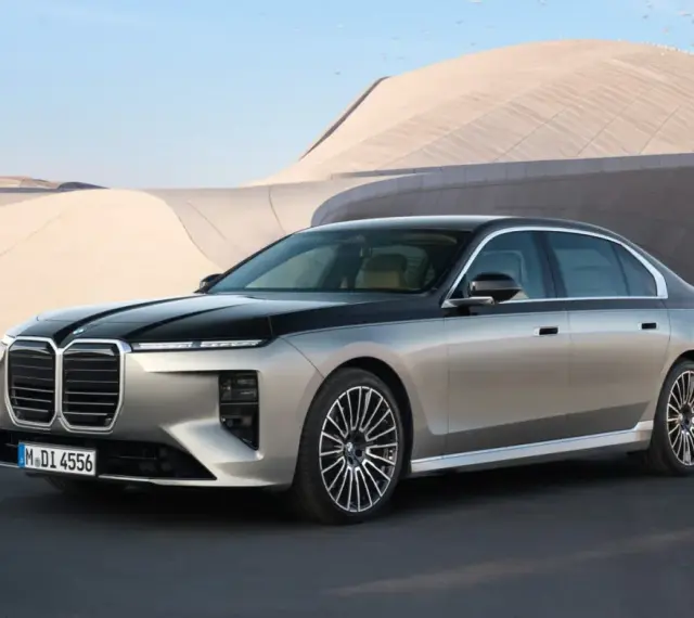 Elegancki BMW 740d w dwukolorowym malowaniu, zaparkowany przed nowoczesnym budynkiem.