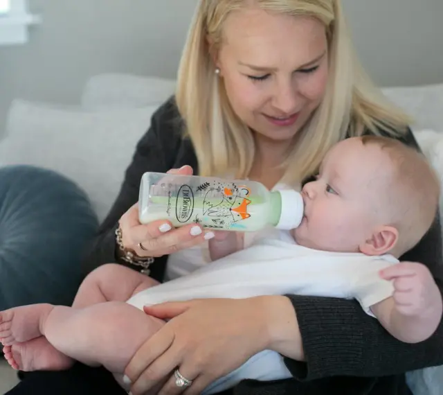 Mama karmi dziecko z butelki antykolkowej Dr Brown's z uroczym motywem lisów.