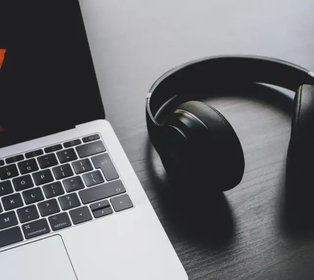 Słuchawki leżą obok laptopa. Może to być sygnał, że występuje brak dźwięku w laptopie i potrzebne są słuchawki do słuchania.