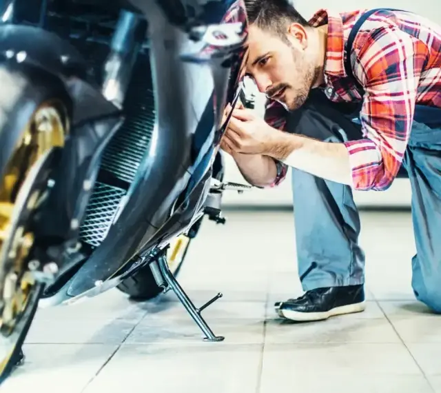 Mechanik sprawdza motocykl. Dowiedz się, ile kosztuje przegląd motocykla, zanim oddasz go do serwisu.