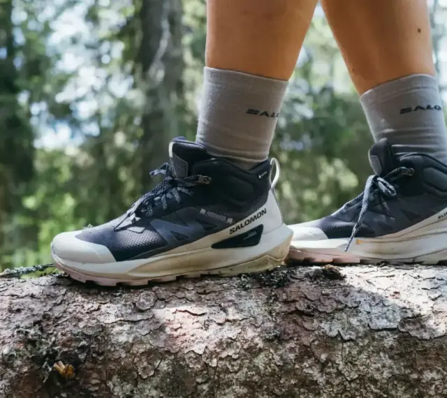 Buty trekkingowe Salomon na pniu drzewa w lesie. Salomon to firma znana z wysokiej jakości obuwia outdoorowego.