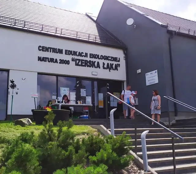 Centrum Edukacji Ekologicznej Natura 2000 "Izerska Łąka" zaprasza. Rodzina wchodzi po schodach do budynku.