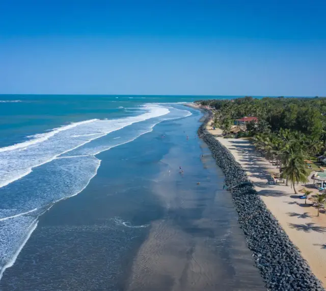 Słoneczne plaże Gambii z palmami i turkusowym oceanem. Ludzie spacerują wzdłuż wybrzeża, ciesząc się pięknem natury.