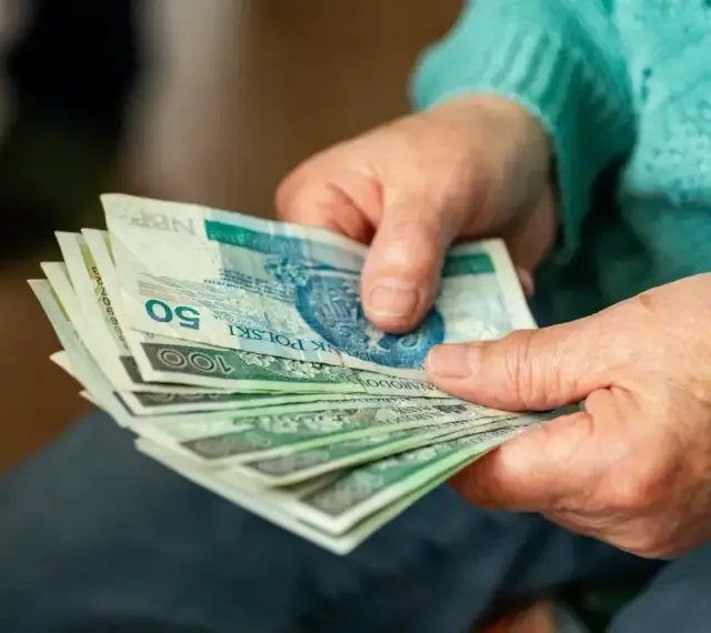 Dłonie starszej osoby liczą banknoty. Zastanawiasz się, ile wynosi dodatek do emerytury za warunki szkodliwe?