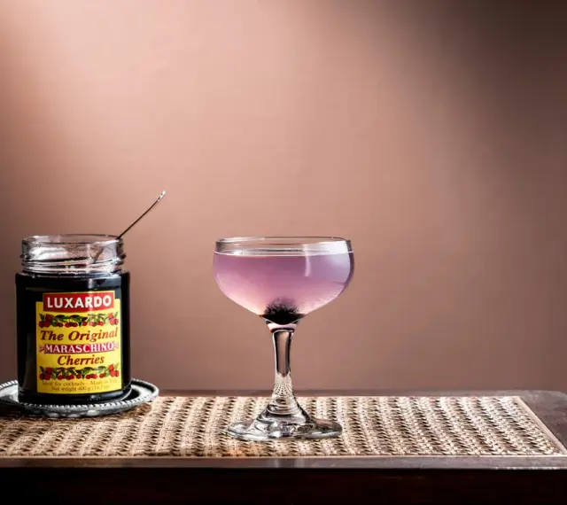 En elegant aviation drink med en burk Luxardo maraschino-körsbär, redo att förhöja smaken.