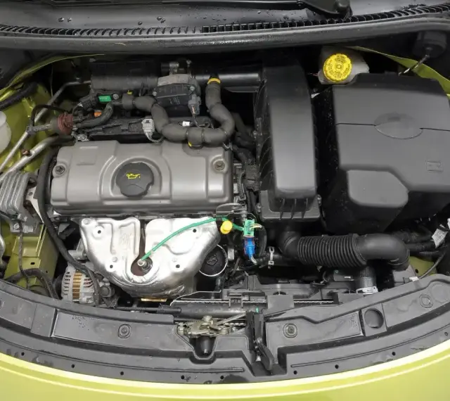 Silnik Peugeot 207, widok z góry. Widać elementy układu dolotowego, pokrywę zaworów i alternator.