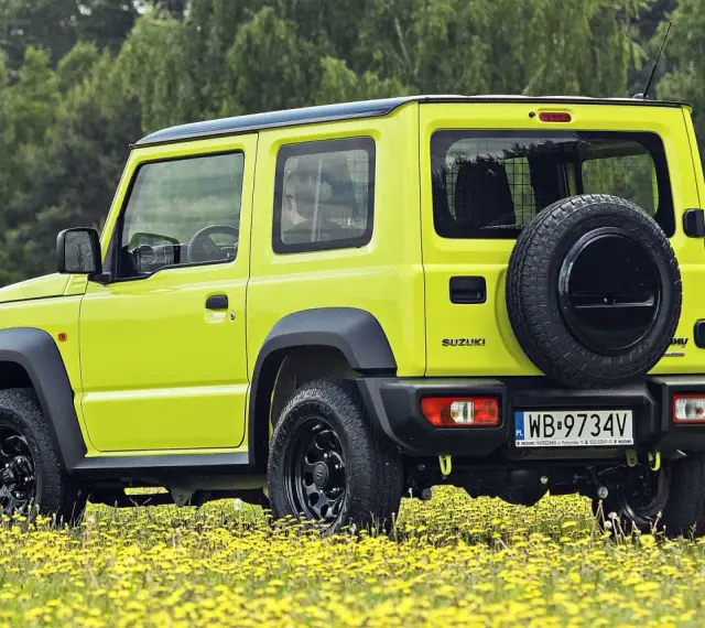 Jaskrawożółty Suzuki Jimny na tle łąki z żółtymi kwiatami. Sprawdź aktualną suzuki jimny cena i wybierz się na przygodę!