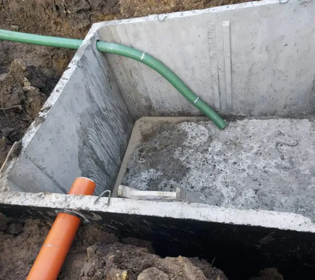 Szambo betonowe 10m3 cena z montażem. Instalacja wkopana w ziemię, widoczne rury doprowadzające.