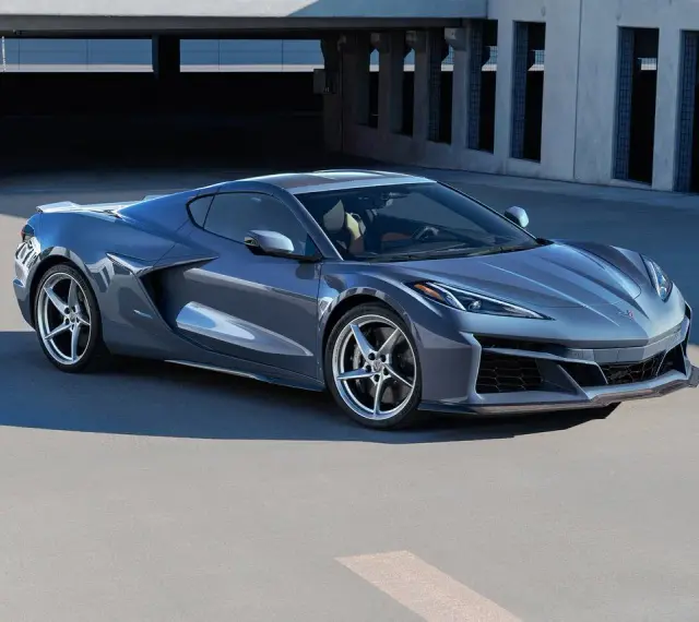 Szary Chevrolet Corvette Stingray z nowoczesnym designem, zaparkowany na tle betonowej architektury.